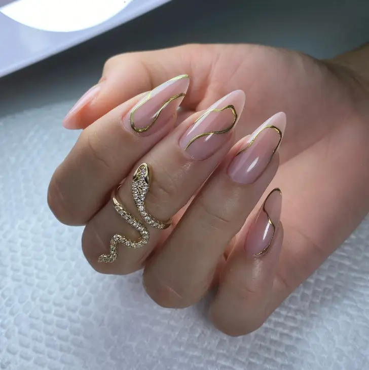 Нейтральный маникюр с золотыми узорами на острых длинных ногтях