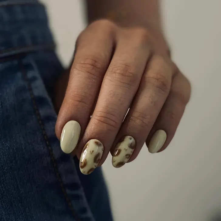 Желтый маникюр с коричневым принтом на овальных ногтях средней длины