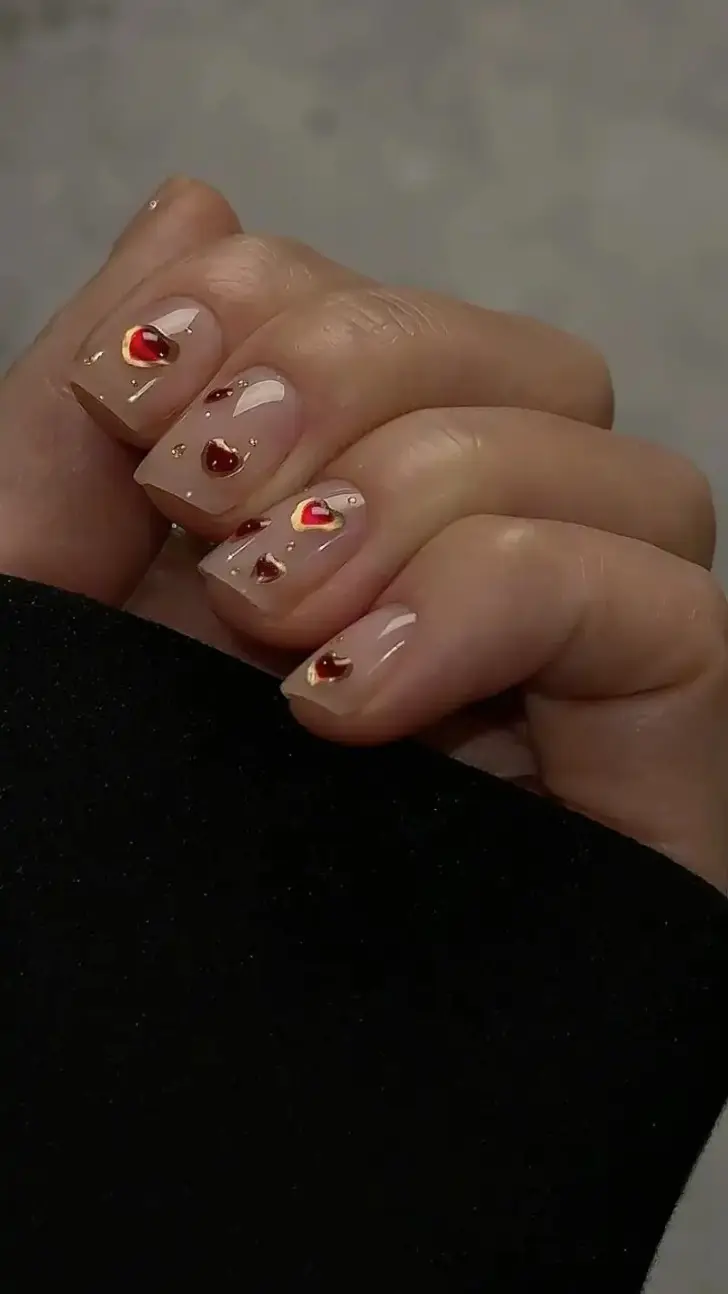 Бежевые ногти с красными сердечками обведенные золотом