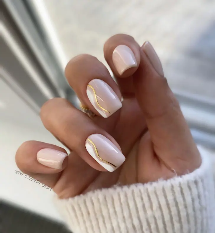 Чистые ногти дополнены легкой белой волной с золотым подчеркиванием