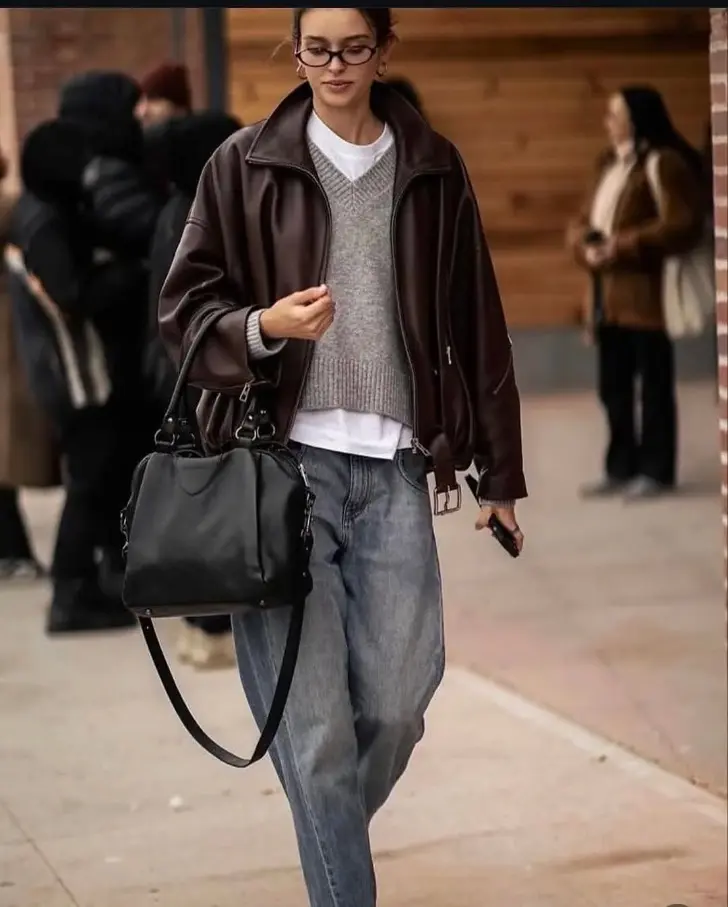 Девушка в любимых джинсах сером джемпере и кожанке