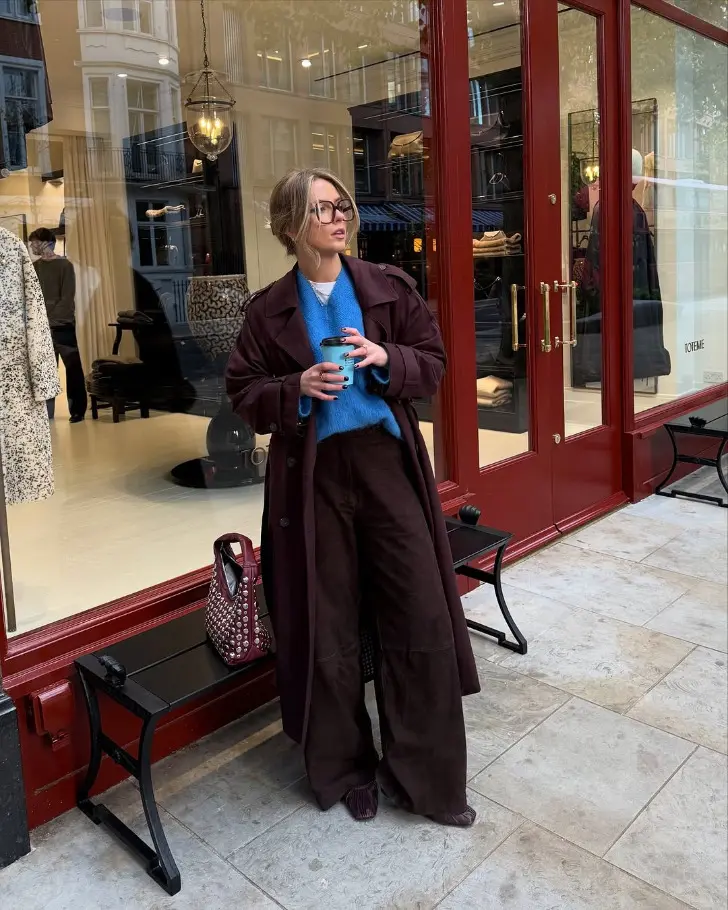 Девушка в синем джемпере фиолетовых брюках и плаще