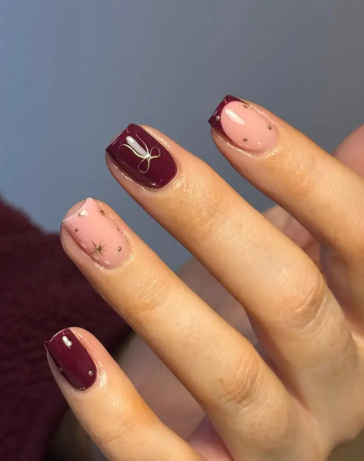 Короткий маникюр на февраль в бордовом цвете украшен золотыми звездами