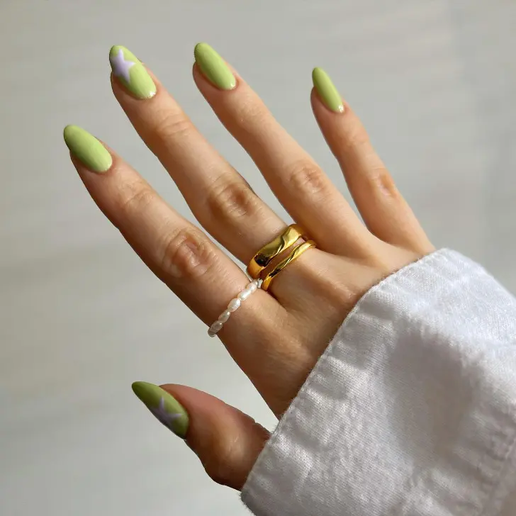 Овальный маникюр цвета васаби с бледно фиолетовой звездой