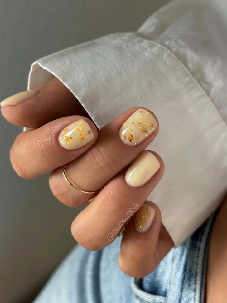 Короткий желтый маникюр с ногтями усыпанными золотой фольгой